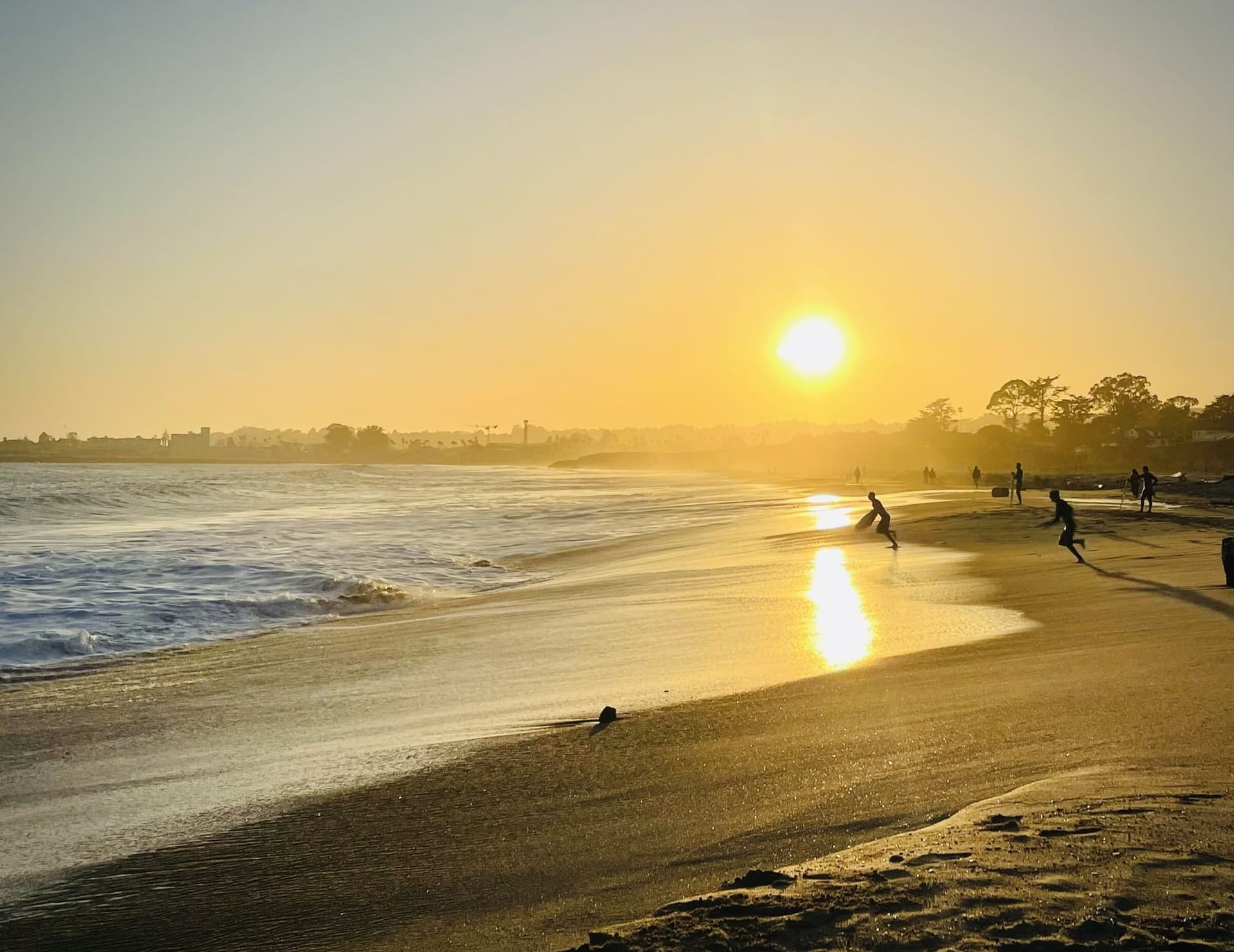 Two runners crossing the wet sand at sunset on a Santa Cruz beach